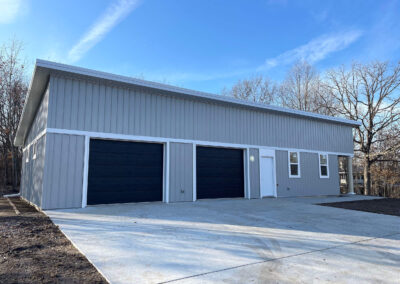 A garage with two garage doors in the middle of the yard.