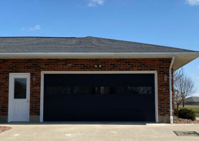 A black garage door in a brick house.