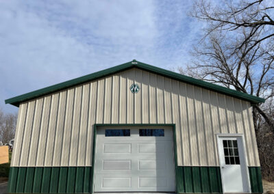 A garage with green siding and a garage door.