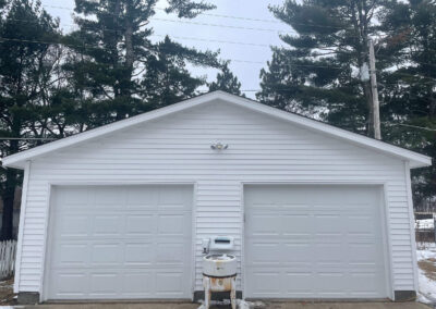 A white garage with two doors and a snow shovel.
