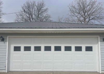 A white garage door with a metal roof.