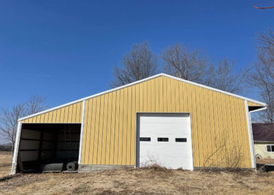 A yellow barn in the middle of a field.