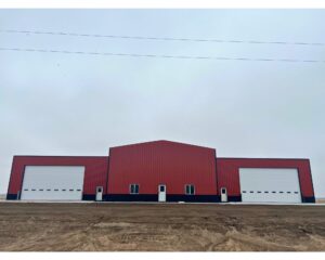 A red building with two doors and a dirt floor.
