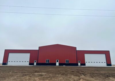 A red building with two doors and a dirt floor.