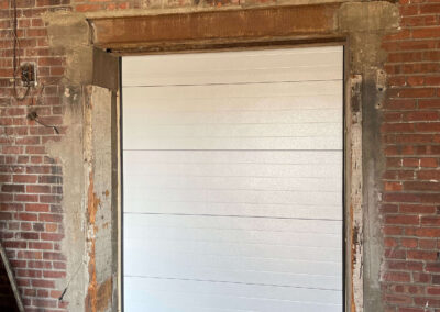 A white garage door in a brick building.