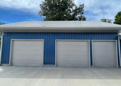 A garage with two blue doors and a metal roof.